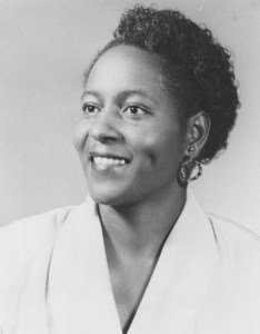 Headshot of Vada Johnson smiling, wearing a white blazer.